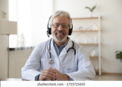 Smiling senior old doctor wears headset looking at camera. Remote online medical chat consultation, tele medicine distance services, virtual physician conference call, telemedicine concept. Portrait. - Shutterstock ID 1723725655
