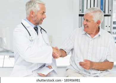 Smiling Senior Patient And Doctor Shaking Hands In The Medical Office