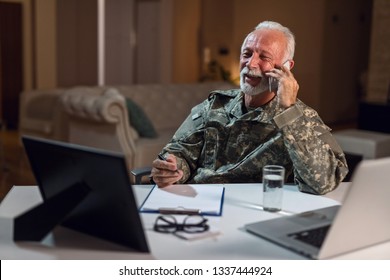 Smiling Senior Veteran In Army Uniform Working In The Office And Talking On Mobile Phone. 