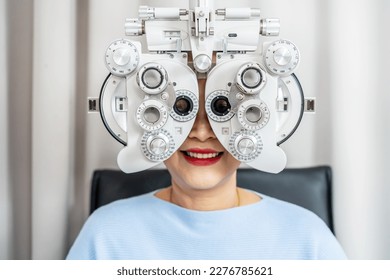 Smiling senior woman asian doing eye test on optical phoropter, checking on her eye with optometry machine - Powered by Shutterstock