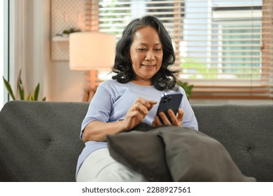 Smiling senior woman in casual clothes using smart phone, browsing wireless internet or chatting online - Powered by Shutterstock