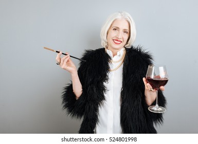 Smiling Senior Woman Drinking Wine And Smoking.