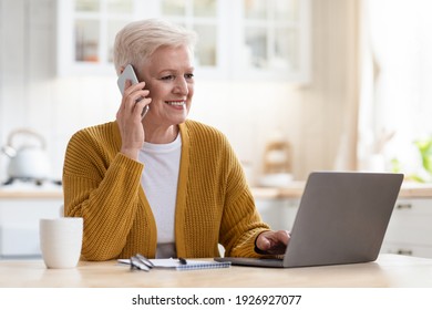 Smiling senior woman having conversation on phone, working on laptop in kitchen, drinking coffee, copy space. Beautiful old lady freelancer working from home, talking with clients on smartphone - Powered by Shutterstock