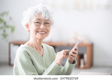 Smiling senior woman holding a smart phone (smartphone), looking at the camera Tap or operate - Powered by Shutterstock