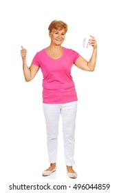 Smiling senior woman holding a tooth model and showing thumb up