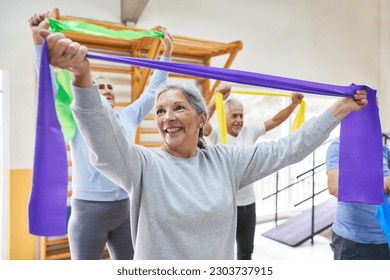 Smiling senior woman and men doing workout with stretch bands at rehabilitation center - Powered by Shutterstock