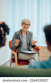 Smiling senior woman psychiatrist talking with her patients during therapy session in the office. Mental health counselor. Psychotherapy services and mental health. Copy space. - Shutterstock ID 2264335027