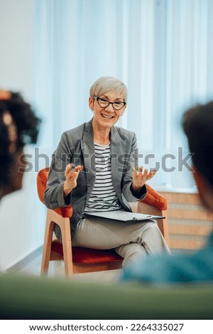 Smiling senior woman psychiatrist talking with her patients during therapy session in the office. Mental health counselor. Psychotherapy services and mental health. Copy space.