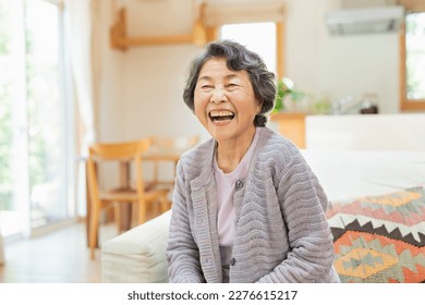 Smiling senior woman sitting on an indoor sofa. - Powered by Shutterstock