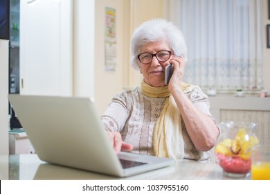 Smiling Senior Woman Using Phone And Laptop At Home.