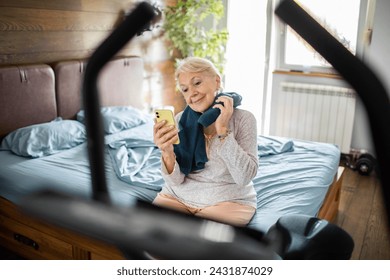 Smiling senior woman using smartphone after home workout - Powered by Shutterstock