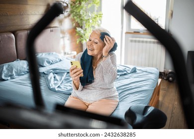 Smiling senior woman using smartphone after home workout - Powered by Shutterstock