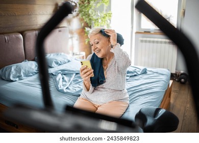 Smiling senior woman using smartphone after home workout - Powered by Shutterstock