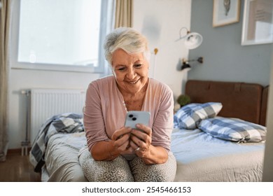 Smiling senior woman using smartphone on the bed at home - Powered by Shutterstock