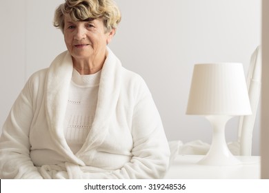 Smiling senior woman in white dressing gown - Powered by Shutterstock