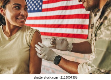 Smiling Servicewoman Getting Vaccinated During The Coronavirus Pandemic. United States Soldier Receiving A Covid-19 Vaccine Shot From A Military Physician In The Army Hospital.