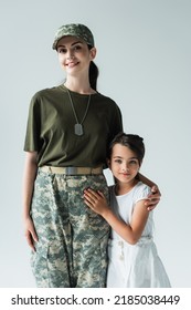 Smiling Servicewoman In Military Uniform Hugging Child Isolated On Grey