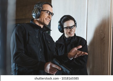 smiling shooting instructor and customer in shooting gallery