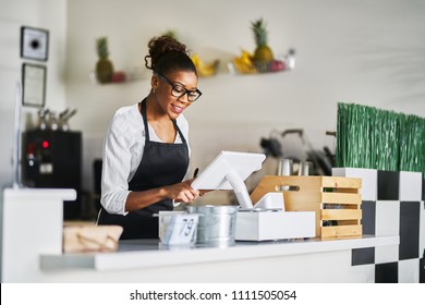 Smiling Shop Assistant Using Pos Point Of Sale Temrinal To Put In Order From Notepad At Restaurant Register