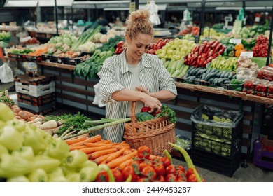 Smiling shopper woman standing next to market stand full of fresh vegetables and putting fresh healthy produce into a wicker shopping basket at farmers market. Customer buying organic veggie at market - Powered by Shutterstock