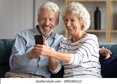 Smiling sincere mature older married family couple holding mobile video call conversation with friends, enjoying distant communication with grown children, using smartphone applications at home. - Powered by Shutterstock