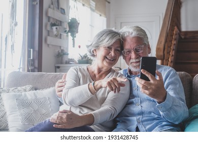 Smiling Sincere Mature Older Married Family Couple Holding Mobile Video Call Conversation With Friends, Enjoying Distant Communication With Grown Children, Using Smartphone Applications At Home.