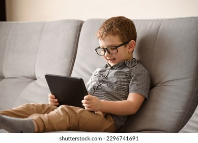 Smiling small boy in the glases looking at tablet - Powered by Shutterstock