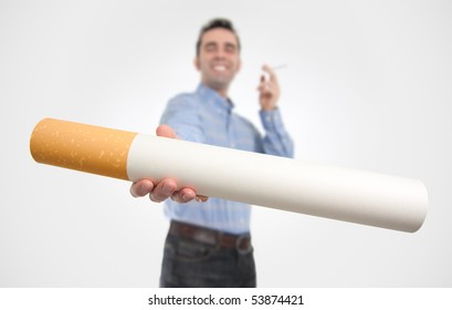 A Smiling Smoker (out Of Focus) Offers A Giant Cigarette (in Focus), Probably To Somebody Who Quit Smoking/shouldn't Smoke. The Big Size Of The Cigarette Equals The Intensity Of The 