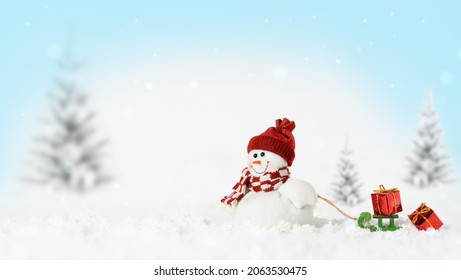 Smiling snowman with sled and gifts on snowy Chistmas background. Copy space