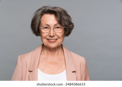 Smiling sophisticated aged business woman in eyeglasses looking at camera headshot close up studio portrait. Happy mature elegant old lady isolated advertising products or services on grey background. - Powered by Shutterstock