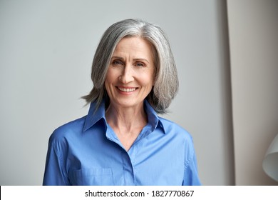 Smiling Sophisticated Mature Grey-haired Woman Standing On Grey Wall Background At Home. Happy Elegant Middle Aged Old Lady Professional Businesswoman Entrepreneur Posing In Office, Headshot Portrait.