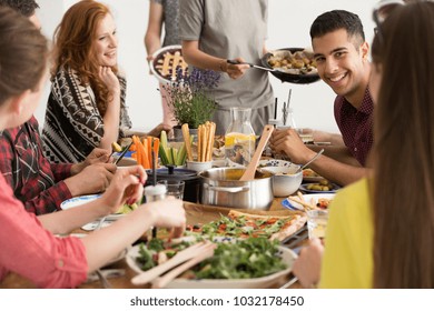 Smiling Spanish Man Eating Lunch With Colleagues During Break At Work