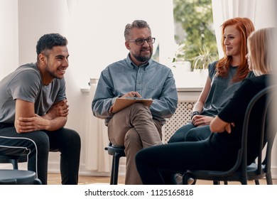 Smiling spanish man talking to his friends during meeting for teenagers with therapist