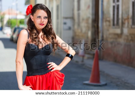 Smiling spanish woman in black dress is posing in the town
