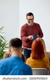 Smiling speaker interacts with audience while presenting concepts in casual environment.