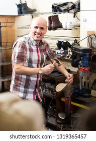 Smiling Specialist Fixing Heel Taps Of Shoes On Machine