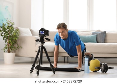 Smiling sports blogger recording fitness lesson with camera at home - Powered by Shutterstock