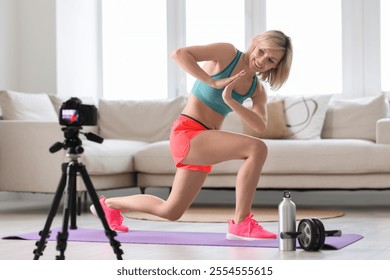 Smiling sports blogger recording fitness lesson with camera at home - Powered by Shutterstock