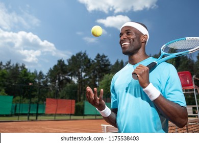 Smiling Sportsman Is Playing Match In Sun. He Is Holding Racket And Throwing Up Ball With Hand. Copy Space In Left Side