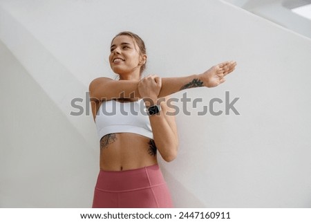 Smiling sportswoman in tracksuit stretching outdoor and preparing to jogging. Healthy life concept