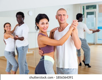 Smiling Sporty Asian Woman Learning To Dance Waltz With Partner In Dancing Class