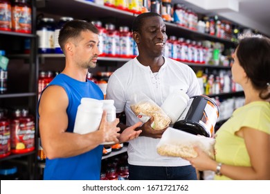 Smiling Sporty Girl And Two Men Speaking About Sports Nutrition  In Sport Nutrition Store