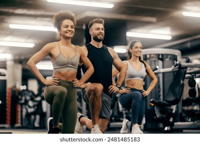 Smiling sporty gym muscular friends kneeling with hands on hips at gym. - Powered by Shutterstock