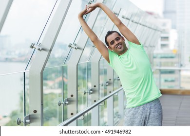 Smiling sporty man stretching body on balcony - Powered by Shutterstock