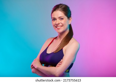 Smiling Sporty Woman In Fitness Sportswear With Arms Crossed. Confident Female Fitness Coach Portrait Isolated On Neon Multicolor Background.