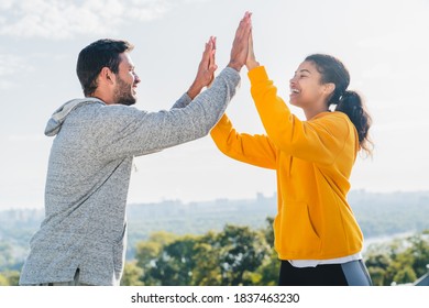 Smiling Sporty Young Couple Taking High Five While Outdoor Workout In The City Park