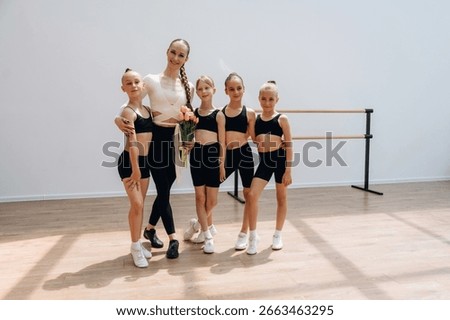 Smiling, standing and posing. Trainer is teaching girls ballet dancing.