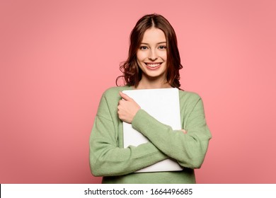 Smiling Student Holding Closed Laptop While Looking At Camera Isolated On Pink