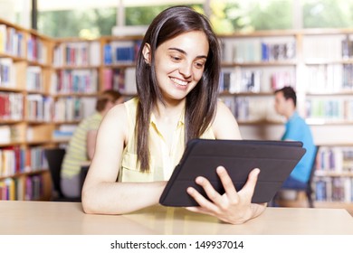 Smiling student using a tablet computer in a university library