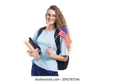 Smiling Student Woman In Glasses With Backpack Holds Books, Notebooks And Flag USA While On White Studio Background